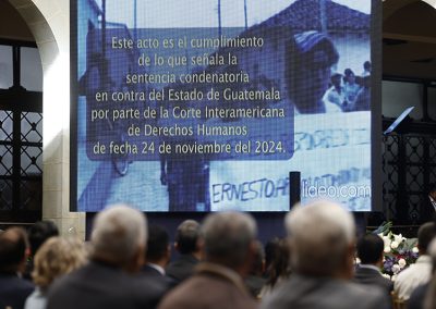 En la imagen se observa una pantalla de gran tamaño que muestra el siguiente texto: “Este acto es el cumplimiento de lo que señala la sentencia condenatoria en contra del Estado de Guatemala por parte de la Corte Interamericana de Derechos Humanos, de fecha 24 de noviembre del 2024”, proyectado durante el acto de disculpas públicas en el Palacio Nacional de la Cultura.
