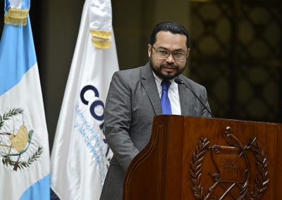 En la imagen se observa a Elvyn Díaz, Director Ejecutivo de la Comisión Presidencial por la Paz y los Derechos Humanos COPADEH, de pie en un atril con el escudo nacional, dirigiéndose al público durante el acto de disculpas públicas del Estado de Guatemala por el caso Pérez Lucas Vs. Guatemala, realizado en el Palacio Nacional de la Cultura.