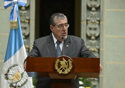 En la imagen se observa al Presidente de la República de Guatemala, señor Bernardo Arévalo, de pie en un atril con el escudo nacional, dirigiéndose al público durante el acto de disculpas públicas del Estado de Guatemala por el caso Pérez Lucas Vs. Guatemala, realizado en el Palacio Nacional de la Cultura.